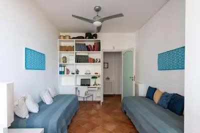 a living room with two beds and a book shelf at Casa Annibale con Vista Mare by Wonderful Italy in Palermo