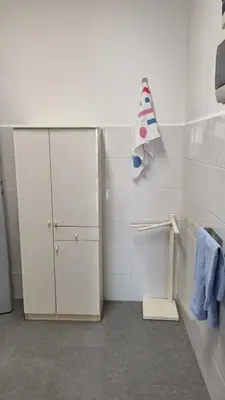 a white bathroom with a cabinet and blue towels at Il Loft di Godrano in Godrano
