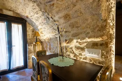 a dining room with a table and a stone wall at Villa Cannamele in Carini