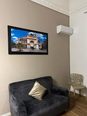 a black couch in a living room with a tv on the wall at Le suite di Alba in Palermo