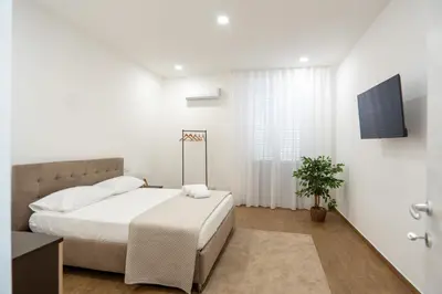 a white bedroom with a bed and a tv at Home1995 in Palermo