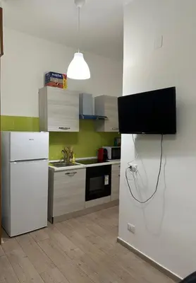 a kitchen with a white refrigerator and a tv on the wall at Orologio21-Soggiorna al teatro Massimo in Palermo