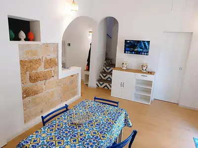 a dining room with a table and a kitchen at Casa Sciàpó in Terrasini