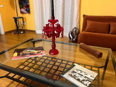 a glass coffee table with a red candlestick on top of it at Maria's apartment alla Magione, appartamento in centro in Palermo