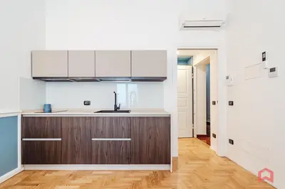 a kitchen with white cabinets and a wooden floor at Nuovissimo Appartamento nel Cuore di Palermo in Palermo