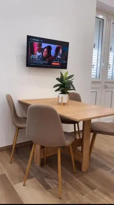 a wooden table with chairs and a tv on a wall at Donna Franca in Cinisi