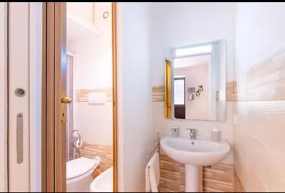 a bathroom with a sink and a toilet and a mirror at La casetta di Andrea in Palermo