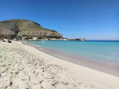a sandy beach with a hill in the background at Il Giardino di Lia in Palermo