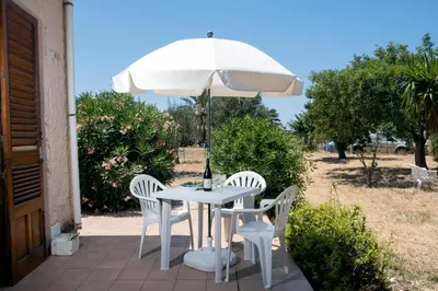 a white table and chairs under an umbrella at I Carrubi in Lascari