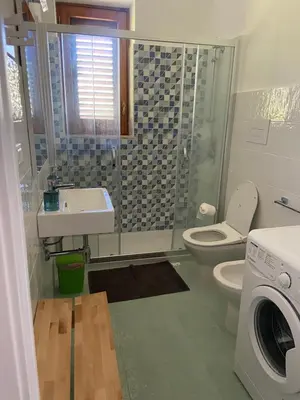a bathroom with a toilet and a sink and a washing machine at I Carrubi in Lascari