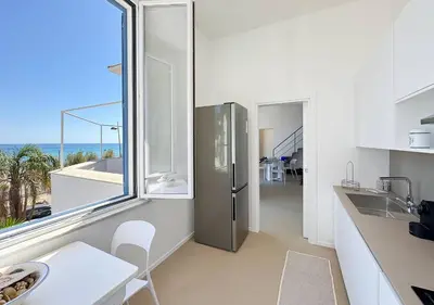 a kitchen with a refrigerator and a view of the ocean at Solemar Sicilia - Villa Regina Elena in Palermo