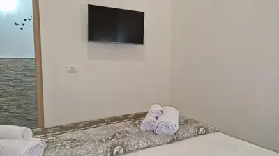 a bed with purple slippers and a tv on a wall at The brothers house appartamento alla Zisa in Palermo