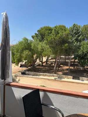 a chair on a balcony with trees in the background at cielo blu in San Vito lo Capo