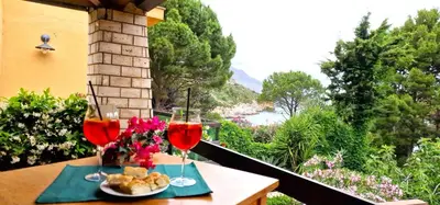 a table with two glasses of wine on a balcony at Villa Dream House Scopello in Scopello