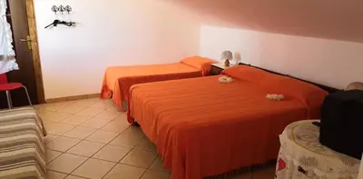 two beds in a hotel room with orange sheets at Casa a Campofelice di Roccella in Campofelice di Roccella