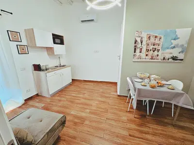 a living room with a table and a kitchen at Oxalis Rooms & Suite in Palermo