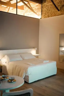 a bedroom with a large white bed and a table at Serafina Suites in Palermo