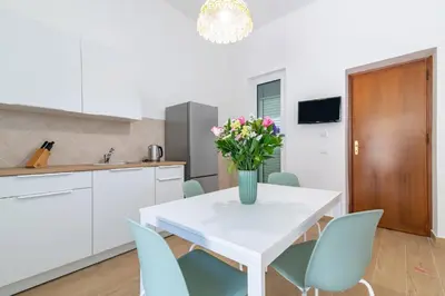 a kitchen and dining room with a white table and blue chairs at GuestHost - Seaview Apartments near Palermo in Palermo