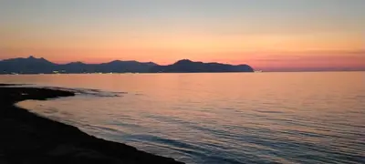 a sunset over the water with mountains in the background at Casa Mirella in Aspra