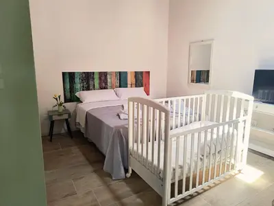 a bedroom with two white cribs and a bed at La Casetta di Lilla in Palermo