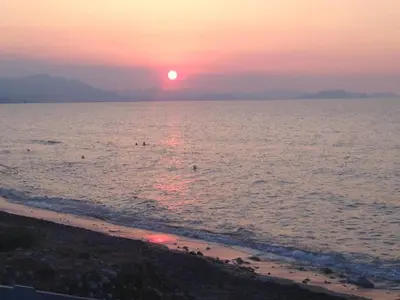 a sunset on the beach with people in the water at Casa Marina in Buonfornello