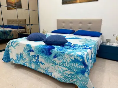 a blue and white bed with blue pillows on it at Piccolo Brasile Home in Capaci