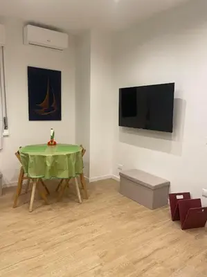 a room with a green table and a flat screen tv at Toselli 32 in Palermo