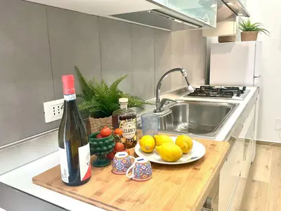 a bottle of wine and a plate of fruit on a kitchen counter at Due passi dal castello a mare in Castellammare del Golfo