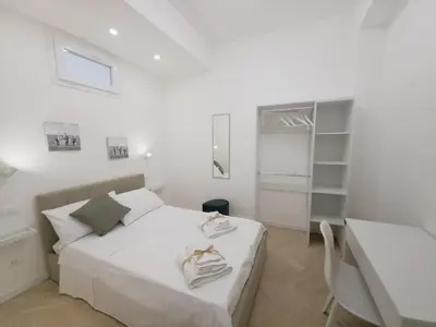 a white bedroom with a bed and a table at Light Charme, Natural Light Apartment a due passi dalla PIAZZA DUOMO in Terrasini