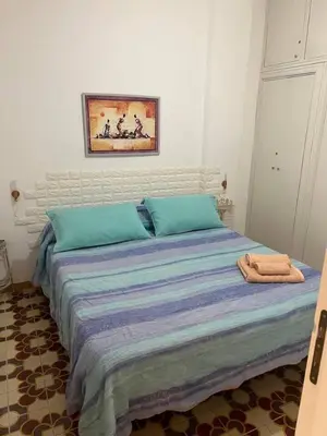 a bed with blue sheets and a painting on the wall at Blue Sea Apartment in Isola delle Femmine