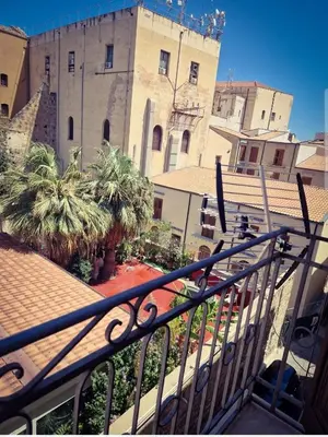 a view of a building with palm trees and a balcony at Love nest cathedral ,in the heart of the city in Palermo