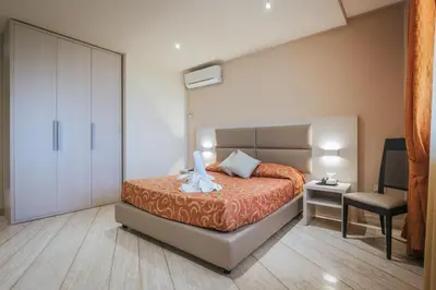 a bedroom with a bed and a desk and a chair at Hotel Costa Azul in Balestrate