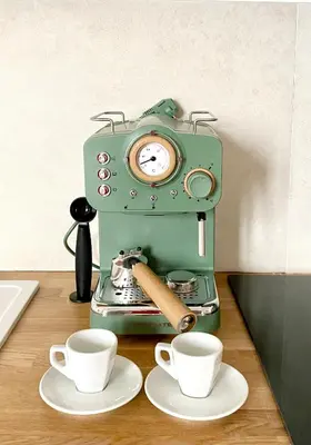 a green coffee maker with two cups on a table at Palazzo 700 in Castellammare del Golfo