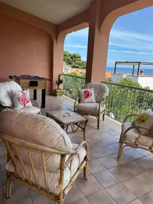 a porch with chairs and a piano on a balcony at Villa del Faro, Capo Zafferano in Santa Flavia