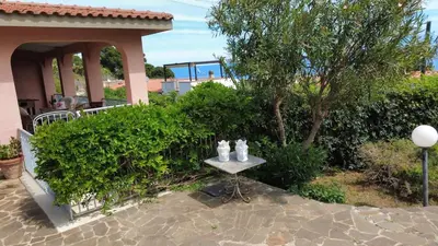 a table with two statues on it next to a house at Villa del Faro, Capo Zafferano in Santa Flavia
