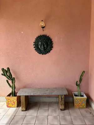 a bench against a pink wall with two potted plants at Villa del Faro, Capo Zafferano in Santa Flavia