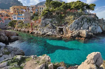 a body of water with buildings on a rocky shore at VFH Blue Breeze holiday home in Porticello
