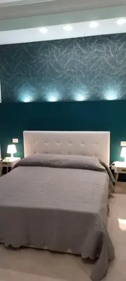 a bedroom with a white bed with a blue wall at Suite Conte di Cavour in Palermo
