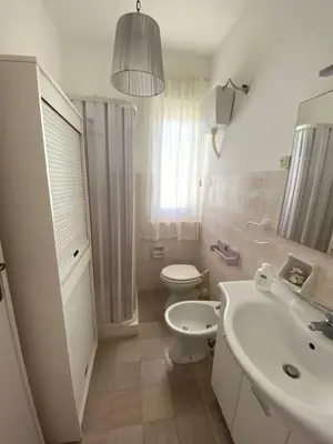 a white bathroom with a toilet and a sink at Casa Bluet on the Sea in Balestrate