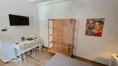 a room with a desk and a shelf and a television at Sichilia House in Palermo