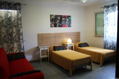 a room with two beds and a red couch at Baia del Sol Balestrate in Balestrate