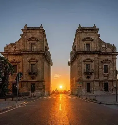 two buildings on a street with the sunset in the background at Higgie House in Palermo