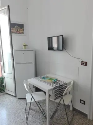 a white table and chairs with a television on a wall at Higgie House in Palermo