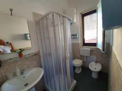 a man taking a picture of a bathroom with a shower at Higgie House in Palermo
