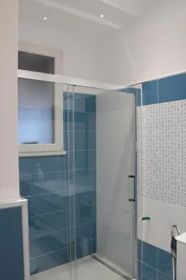 a bathroom with a glass shower with blue tiles at Casa Carmela Mondello in Palermo