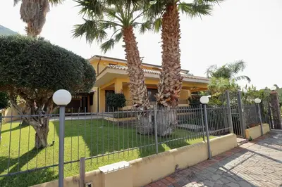 a fence in front of a house with palm trees at Villa Belorizzonte - Relax & Sea in Mandra Capreria