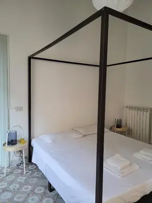 a bed with a black frame and white sheets at MojoCoHouse in Palermo