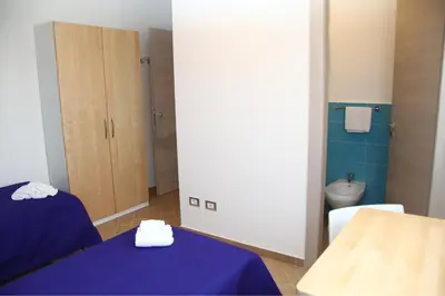 a room with two beds and a bathroom with a toilet at B&B Menta & Peperoncino in Partinico