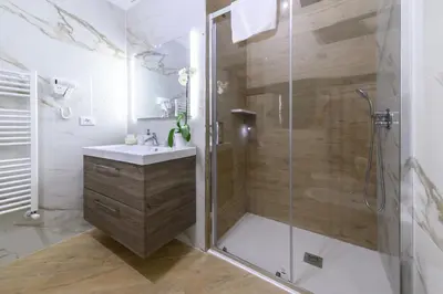 a bathroom with a shower with a sink and a glass shower stall at Oros rooms in Palermo