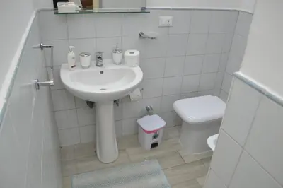 a white bathroom with a sink and a toilet at La Dimora di Alice in Palermo
